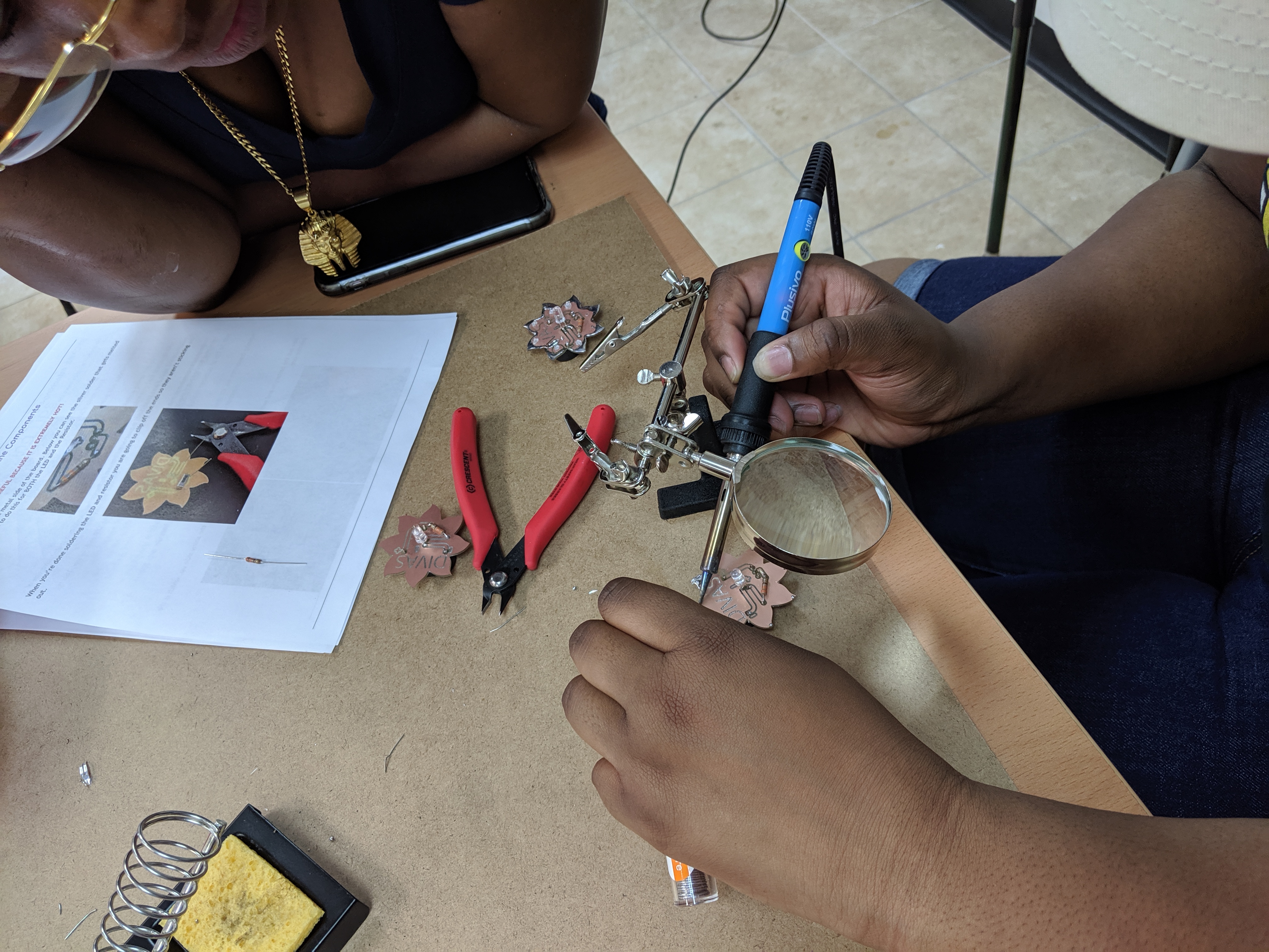 Soldering Station at the Makerspace Launch person soldering an LED circuit board with the DIVAs logo